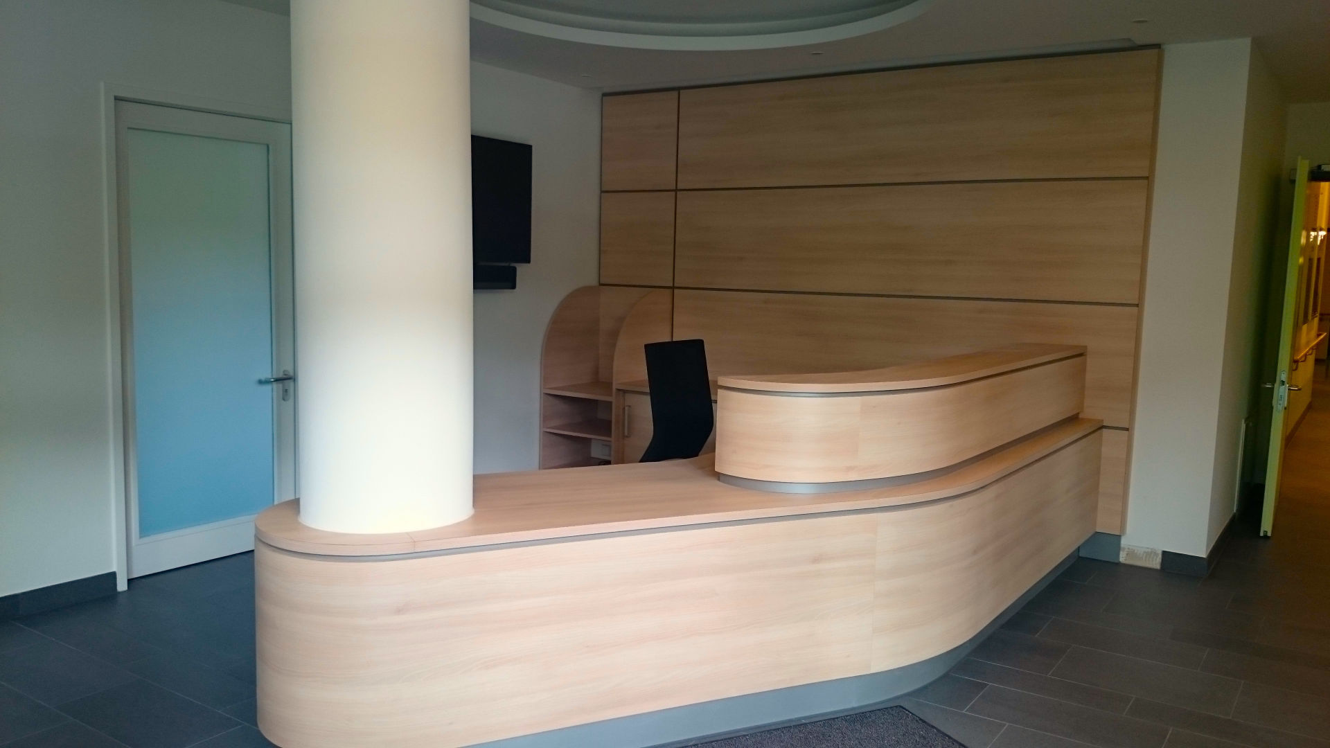 Ein weiteres Bild einer Praxis. Zu sehen ist ein gro&szlig;er, abgerundeter Tisch, der eine S&auml;ule umschlie&szlig;t.